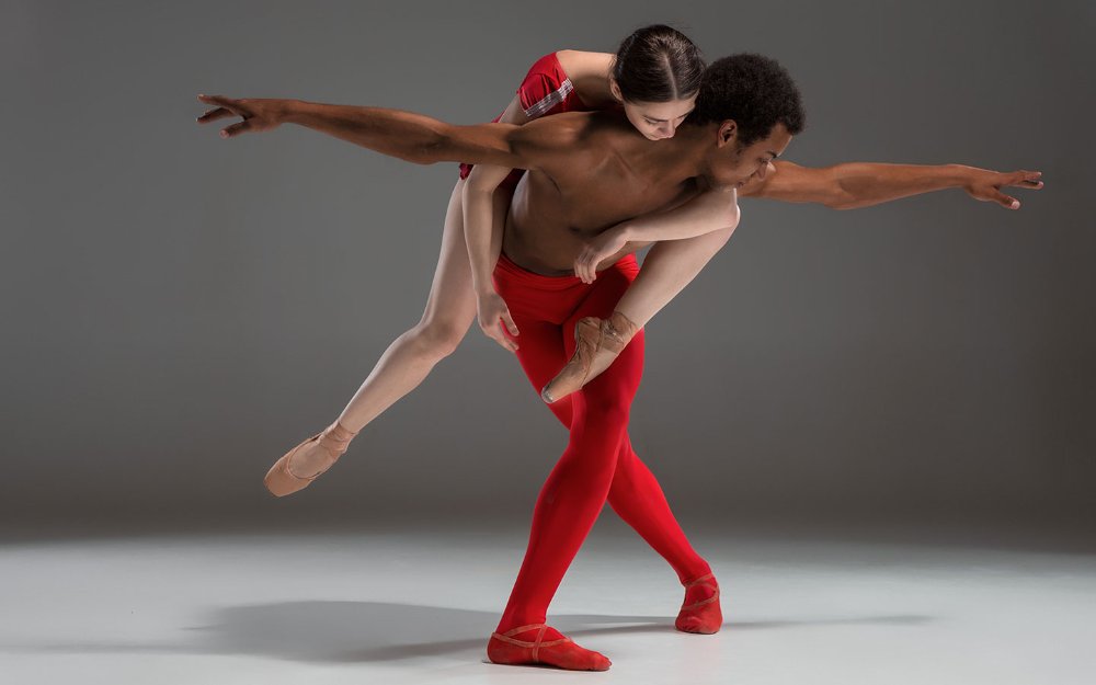 Couple dansant au ballet en rouge, femme sur le dos d’un homme