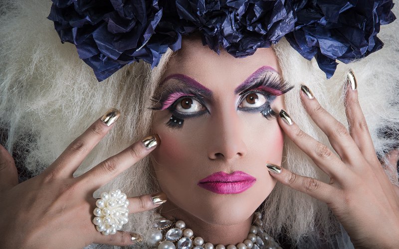 Uma drag queen é mostrada com maquiagem e unhas na imagem