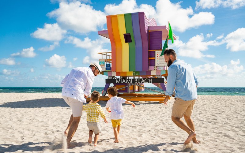 LGBTQ 家庭站在彩虹救生员旁边 Miami Beach